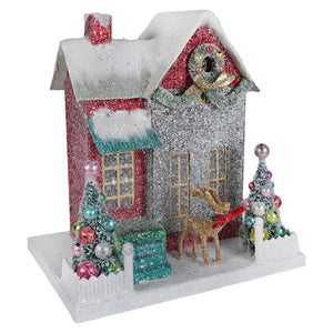 Merry bright glitter cottage figurine with red silver facade snow dusted roof wreath and colorful ornamented trees