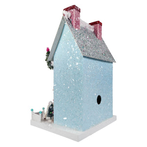 A light blue glittery birdhouse with pink sparkly chimneys and silver roof featuring cody foster merry reindeer chateau decoration