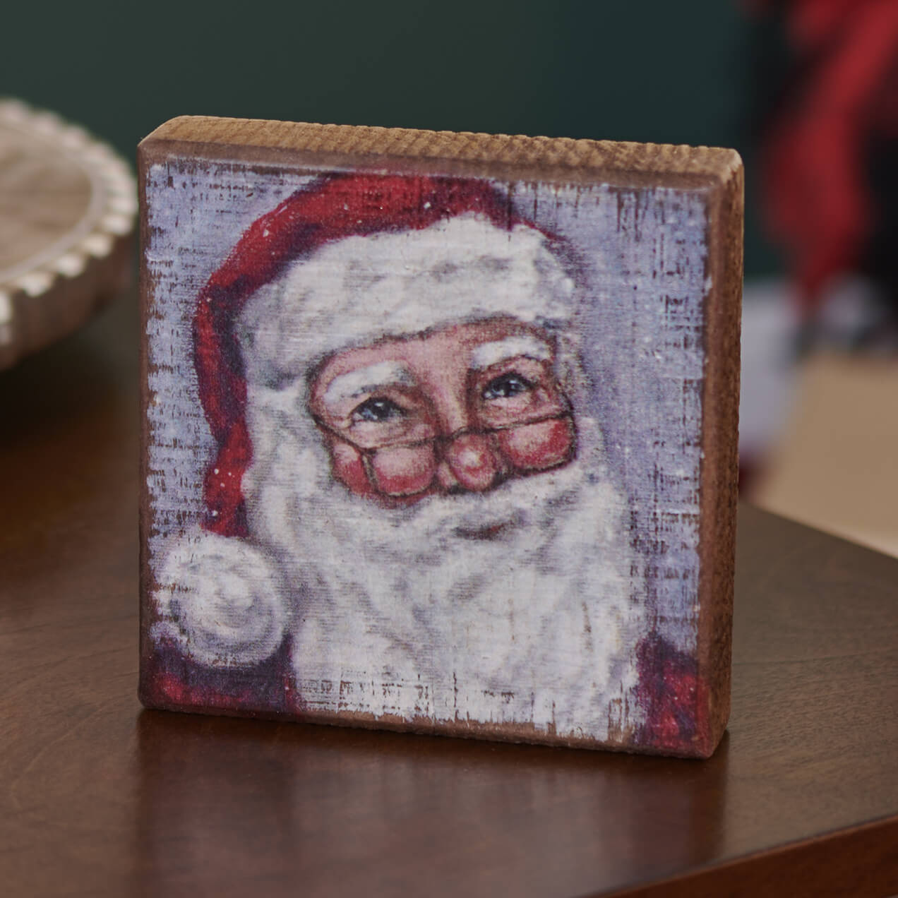 Wooden block with a painted portrait of Santa Claus on its face.