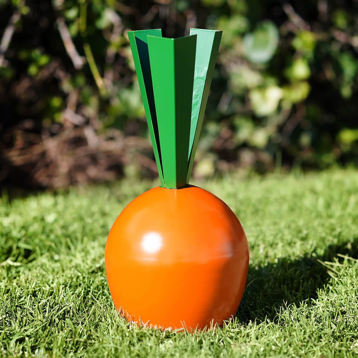 Orange carrot-shaped decorative object with geometric green leaves.