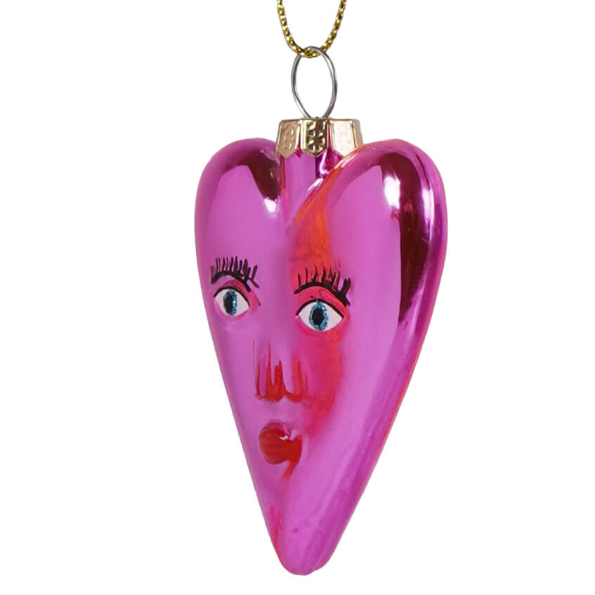 Mi amor heart glass ornament is a glossy pink heart ornament with painted blue eyes black lashes and a red mouth perfect for valentine’s day