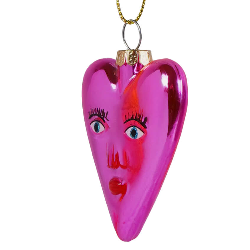 Mi amor heart glass ornament is a glossy pink heart ornament with painted blue eyes black lashes and a red mouth perfect for valentine’s day