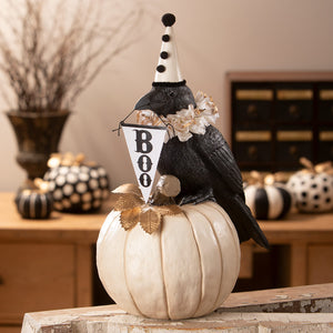 Black messenger crow figurine wearing white polka dot party hat holding boo banner on off white pumpkin by bethany lowe halloween