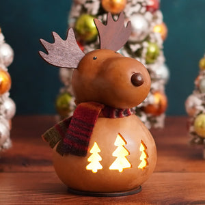 A warm-toned rustic wooden moose gourd lantern with tree cutouts and a red green plaid scarf from meadowbrooke gourds