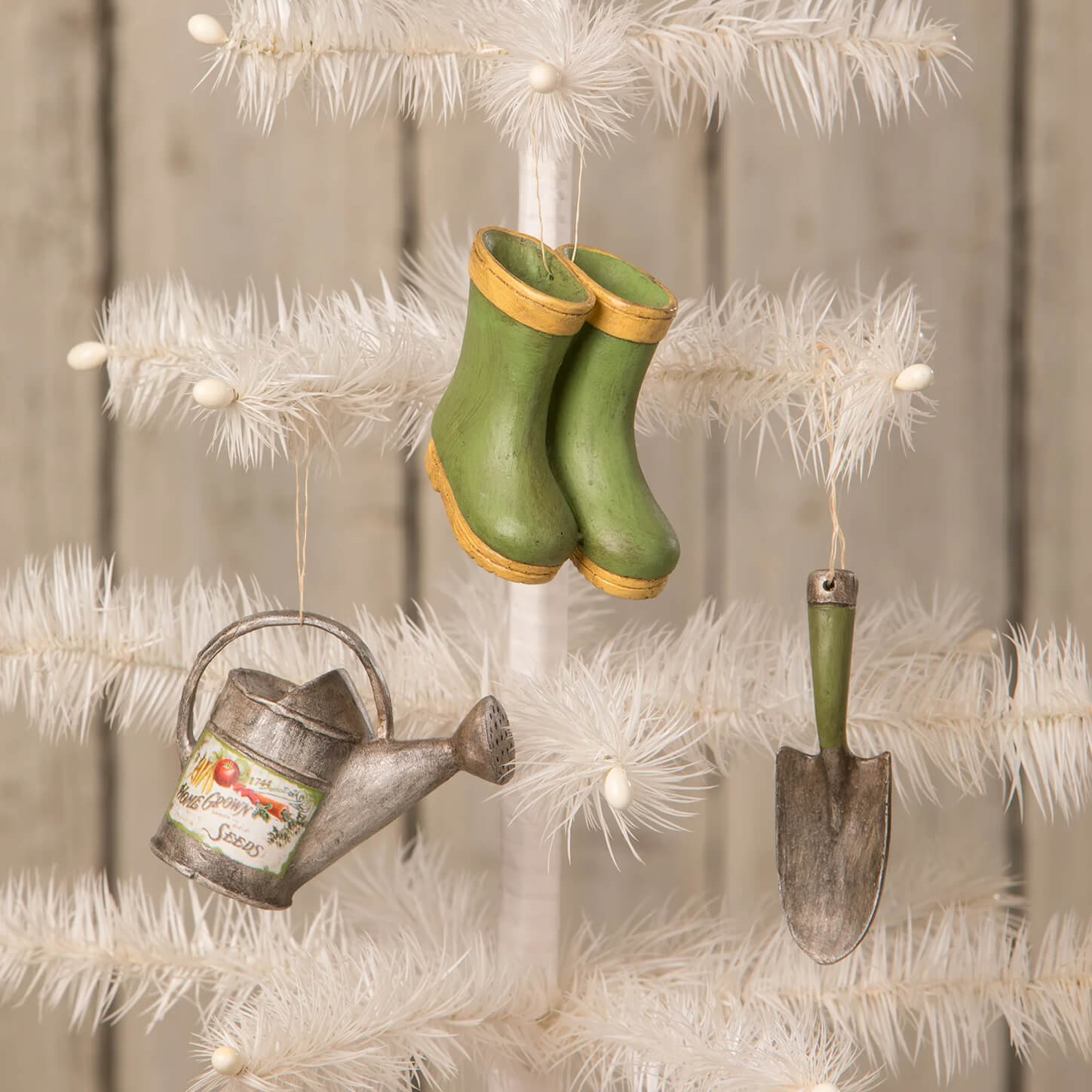 Green rubber boots with yellow trim mini garden ornaments hanging on white tree by bethany lowe designs spreading holiday cheer