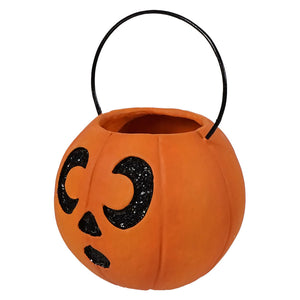 Mini surprised pumpkin bucket ornament is an orange plastic corn pumpkin bucket with black glittery face and wire handle by bethany lowe