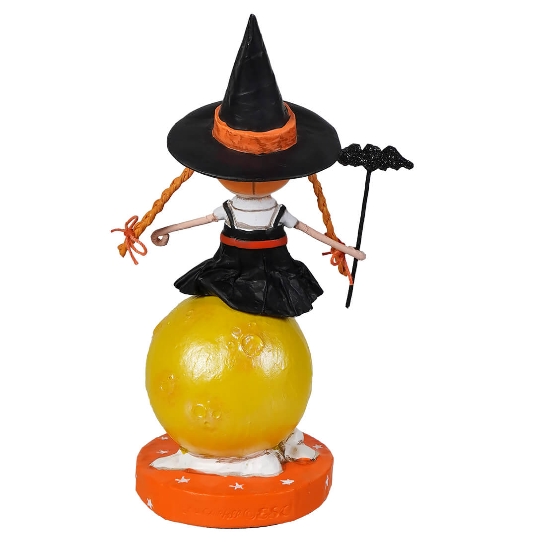A lori mitchell halloween witch figurine with orange braided hair and black dress standing on a yellow moon sphere from mischief on the moon