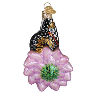 Delicate christmas glass ornament with a black and gold monarch butterfly on a glittery lavender flower center green