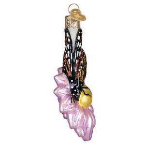 Delicate christmas glass ornament with a monarch butterfly in black white and gold on a shimmering pink flower