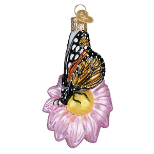 Detailed christmas glass ornament featuring a monarch butterfly with black and orange wings on a pink flower ornament