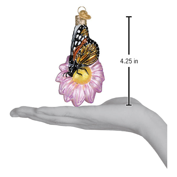 Delicate christmas glass ornament featuring a monarch butterfly with vibrant orange and black wings on a pink flower ornament