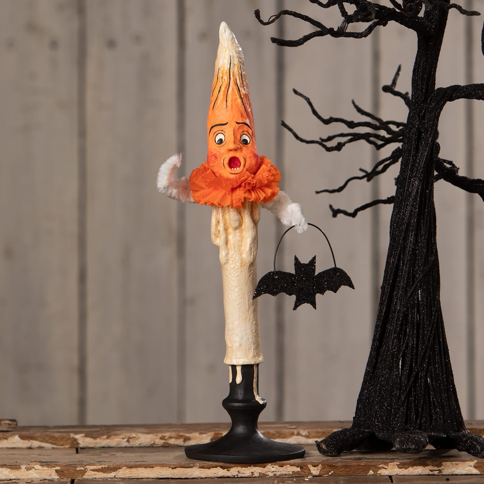Orange and cream mr flame candle figurine with surprised face wearing orange ruffled collar and holding black bat basket by bethany lowe halloween