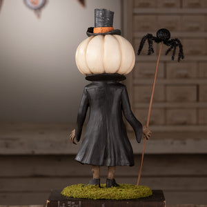 A whimsical halloween figural decor with cream pumpkin head, black top hat, long coat, and spider-topped stick for halloween pumpkins and gourds
