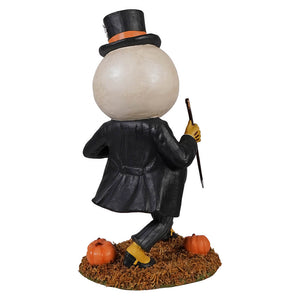 A whimsical harvey moon man halloween snowman figurine in black top hat orange band black coat holding cane with pumpkins