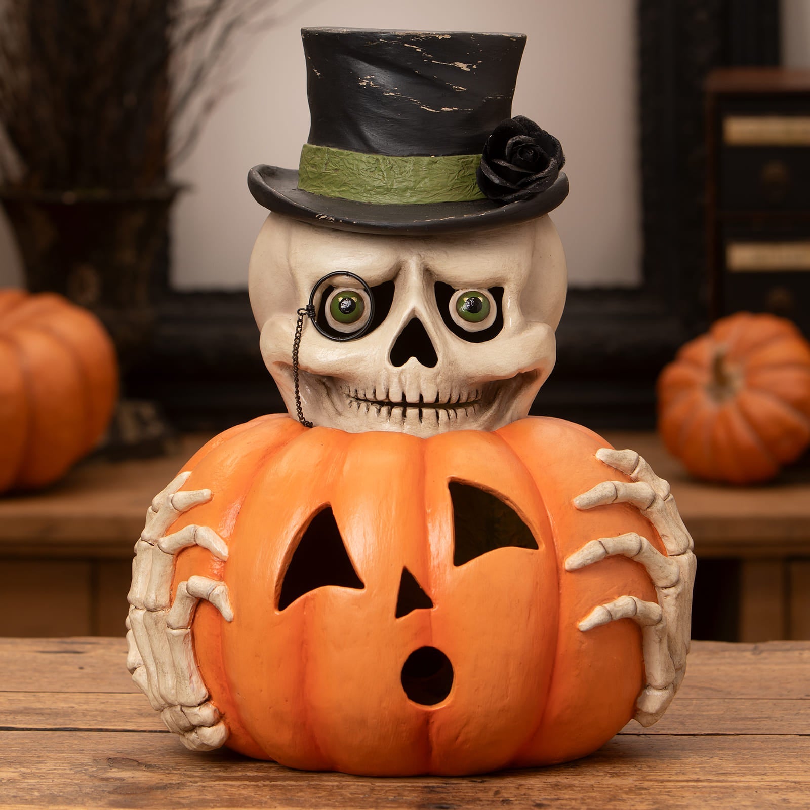 Mr skully skeleton decor figure wearing black top hat with green band holding orange halloween pumpkin ornament
