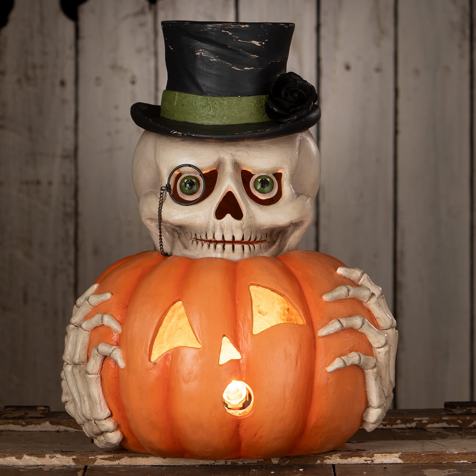 Mr skully skeleton decor figure in white with black top hat holding a lit orange halloween pumpkin lantern