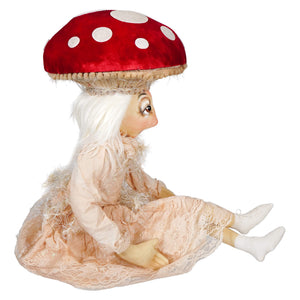 A whimsical myra mushroom doll with long white hair in a peach lace dress sits under a red polka dot mushroom cap by joe spencer gallerie ii design