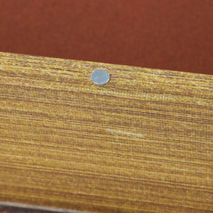 A small silver metal fastener on a wood grain surface next to the naughty or nice book box set nice book box