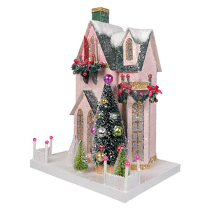 Pink christmas village house by cody foster with glittery green roof snow details and festive garlands with red bows