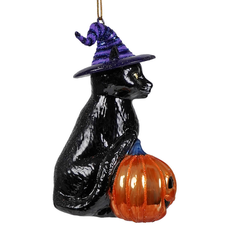 Black glass halloween cat ornament with purple glittery witch hat sitting beside an orange pumpkin by kurt adler noble gems