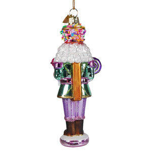A festive glass nutcracker cupcake ornament with colorful sprinkles and glittery purple pants from noble gems™ collection