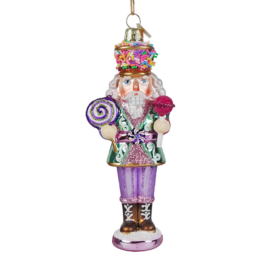Noble gems™ glass nutcracker ornament with glittery purple green outfit holding lollipops and topped with rainbow sprinkle hat