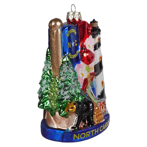 Vibrant north carolina glass ornament featuring blue state flag green pine trees black bear and striped lighthouse