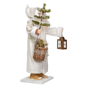 White figurine of old man winter santa in a long hooded robe holding christmas tree and basket by bethany lowe designs