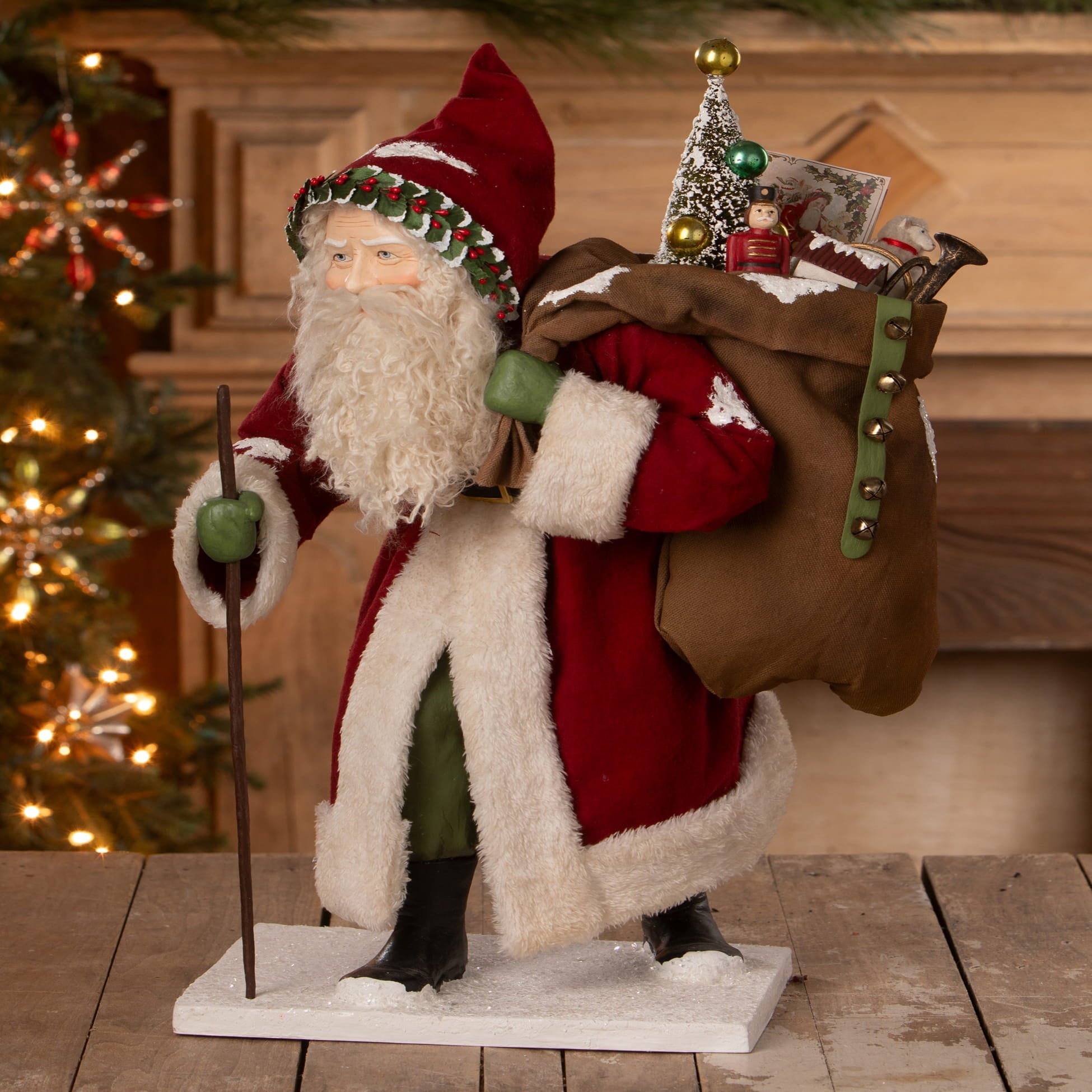 Old st nick santa figure by bethany lowe designs with red and white suit green hat and bag of folk art toys