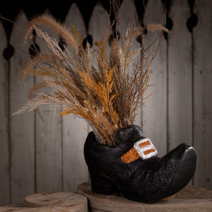 Black glittery paper mache old witch shoe vase with gold white buckle filled with dried grasses for halloween witch decor