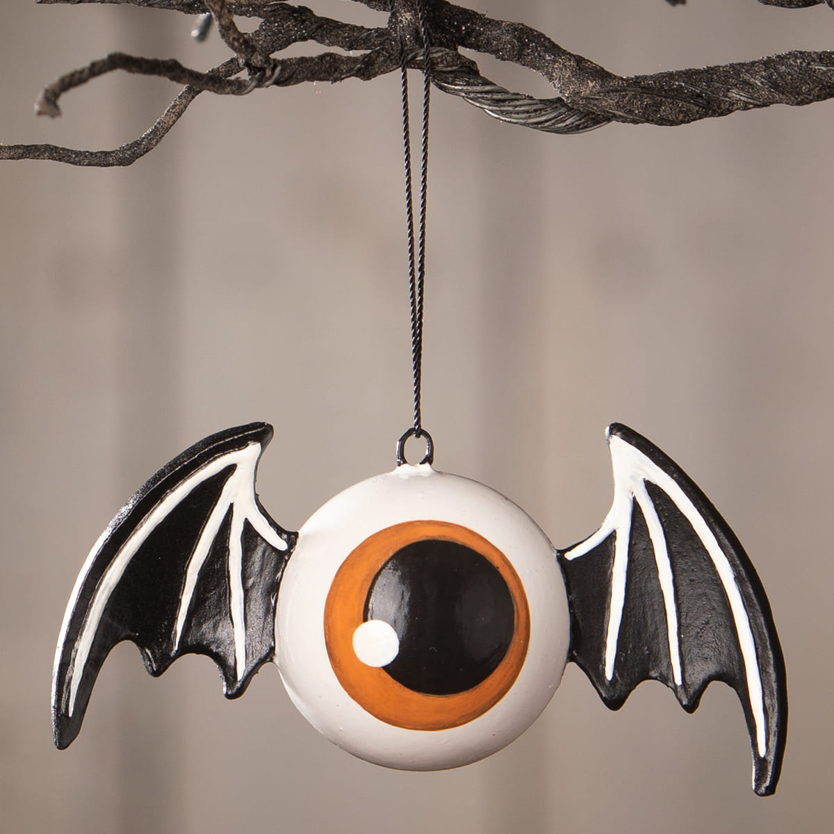 A white glossy eyeball bat ornament with dramatic black-and-white wings and orange black details by bethany lowe designs