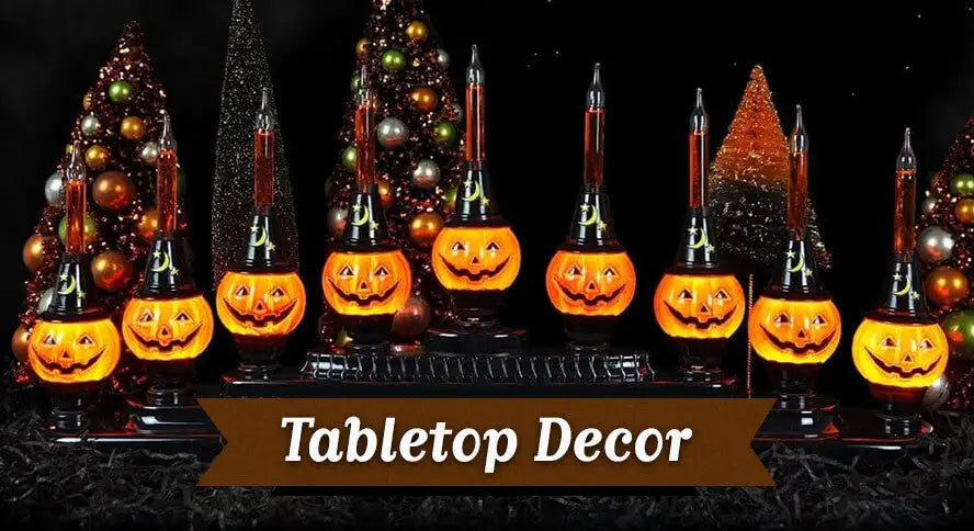 Halloween tabletop décor featuring illuminated jack-o'-lantern candelabra and vintage-inspired bottle brush trees.