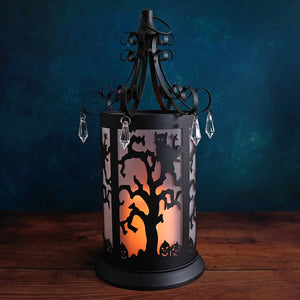 Decorative Halloween-themed lantern with silhouettes of trees, owls, and pumpkins illuminated from within.