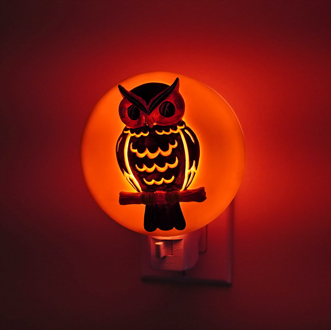 Owl-shaped night light with glowing orange background and dark silhouette.