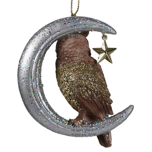 A glittery silver moon ornament with a brown owl perched on it and a small golden star christmas ornament