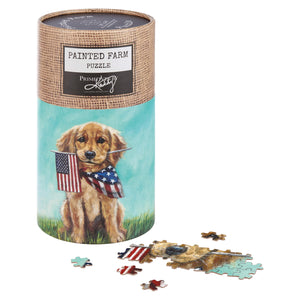Cylindrical puzzle container featuring artwork of a patriotic golden puppy holding an American flag and wearing a stars-and-stripes bow tie.
