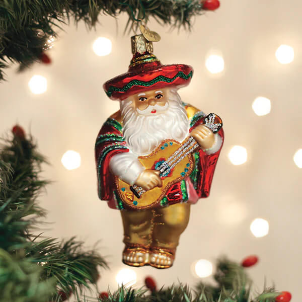 A festive glass papa noel ornament with a red and green sombrero holding a glittery guitar and wearing gold pants