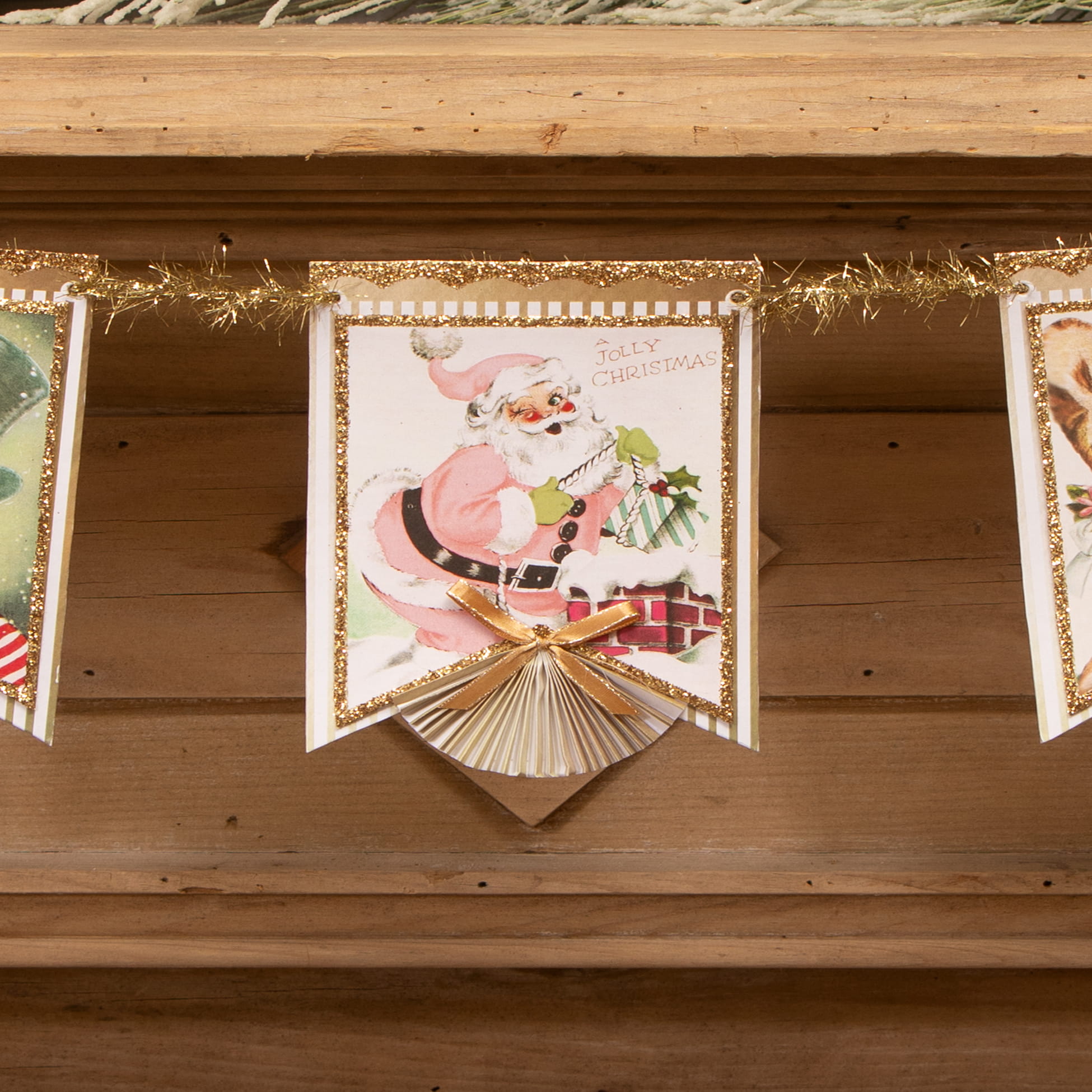 A pastel retro garland by bethany lowe design featuring a vintage-style pink santa with gold glitter trim and ribbon bow