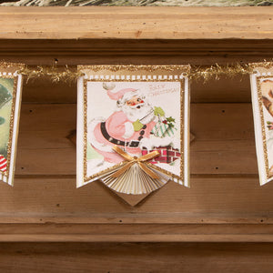 A pastel retro garland by bethany lowe design featuring a vintage-style pink santa with gold glitter trim and ribbon bow
