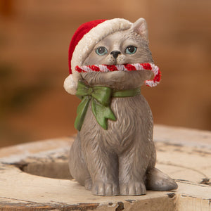 A gray ceramic bethany lowe design kitty sitting with a red santa hat candy cane and green bow peppermint kitty