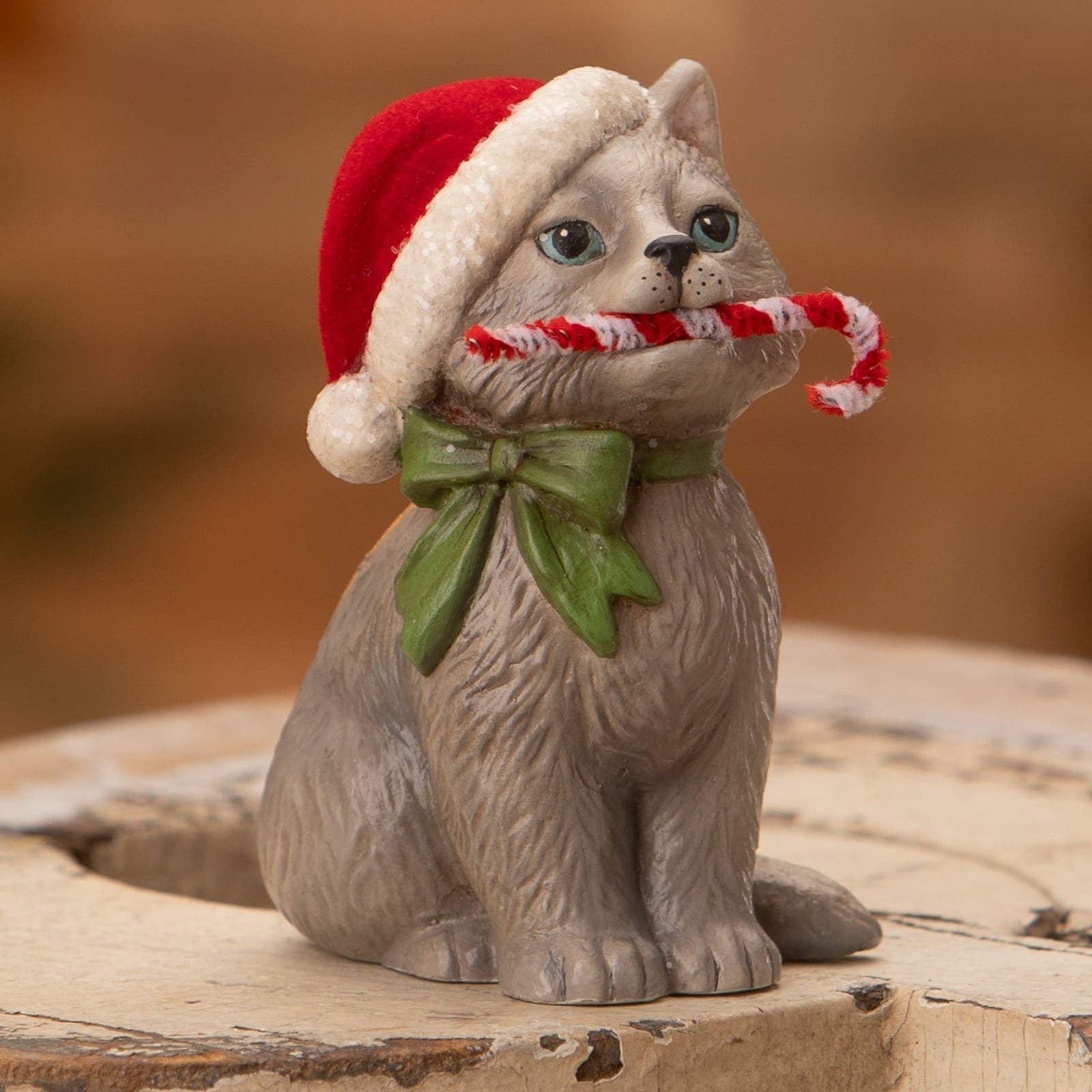 Gray ceramic kitty figurine with red white santa hat and green bow holding candy cane by bethany lowe design