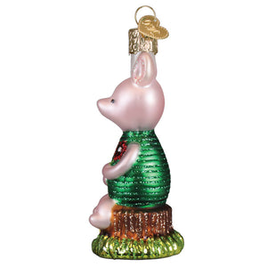 Pink glass piglet ornament wearing green textured vest with red glitter heart standing on tree stump base perfect for christmas glass ornament or toys & fun miscellaneous ornaments