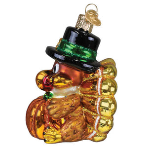 A glossy orange and gold glass pilgrim turkey ornament wearing a black top hat with green trim for christmas decor
