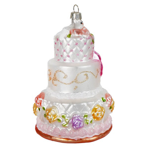 A three-tiered white glass bow wedding cake ornament with pink glitter, colorful flowers, and a silver top cap