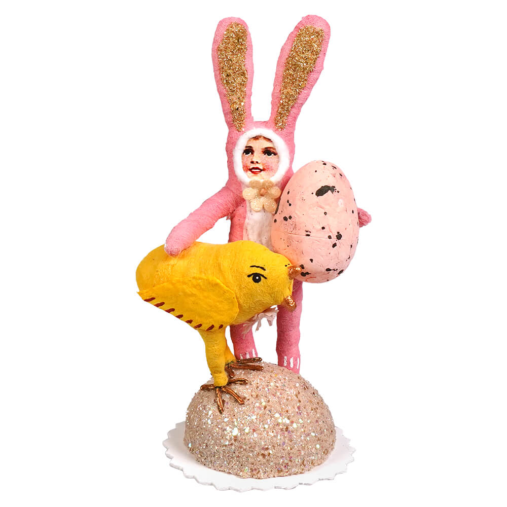 Pink bunny child handcrafted folk art figurine with glittery ears holding a speckled pink egg on a sparkly base
