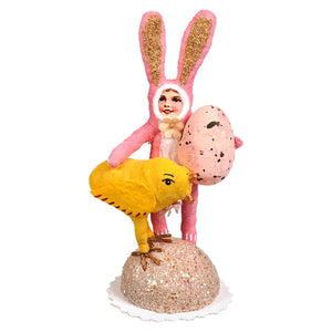 Pink bunny child handcrafted folk art figurine with glittery ears holding a speckled pink egg on a sparkly base