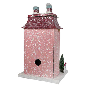 Pink chateau house birdhouse with red shingled roof, snow-capped chimneys, and a miniature green tree in village style