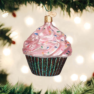 Pink chocolate cupcake christmas glass ornament with pink frosting colorful sprinkles and glittery green liner hanging on tree