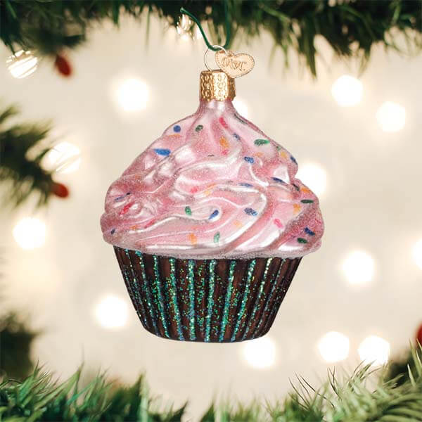 Pink chocolate cupcake christmas glass ornament with pink frosting colorful sprinkles and glittery green liner hanging on tree