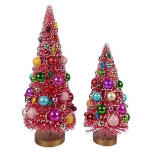 Two pink frosted decorated bottle brush christmas trees with colorful ornaments on gold bases for holiday decor